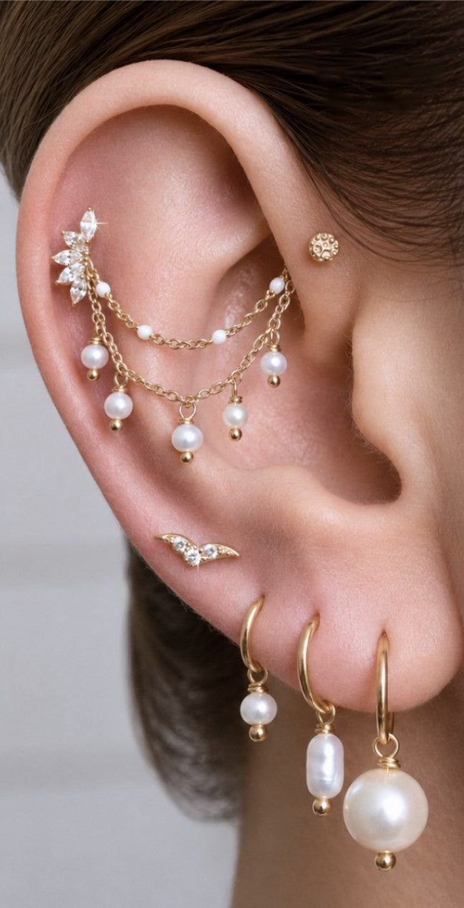 A curated ear with gold and pearl jewelry