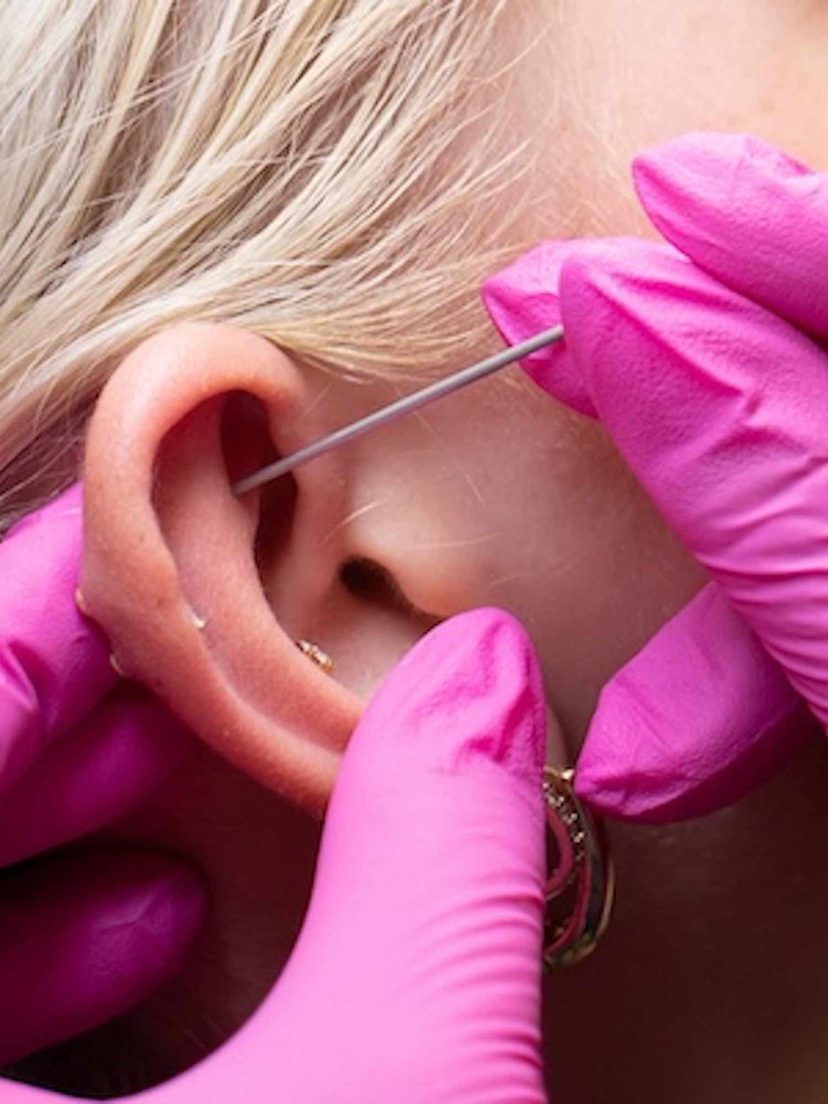 ear cartilage piercing with pink gloves