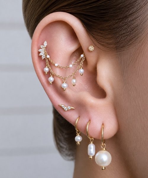 An ear styled with gold chains, pearl drops, crystal studs and small gold hoops